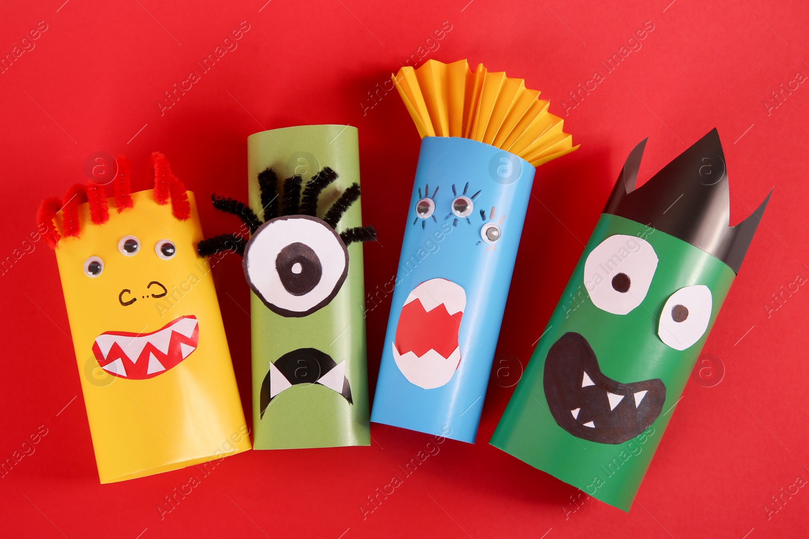 Photo of Funny monsters on red background, flat lay. Halloween decoration