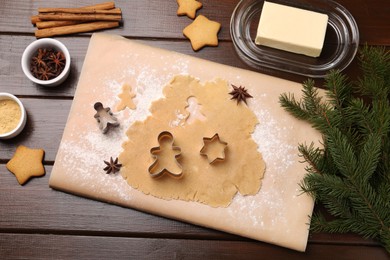 Photo of Making Christmas cookies. Flat lay composition with cutters and raw dough on wooden table