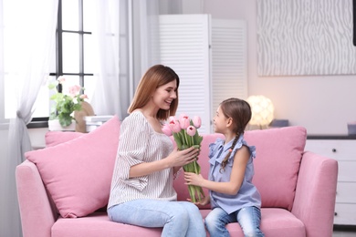 Photo of Happy mother and daughter with flowers at home. International Women's Day