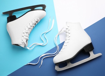 Photo of Pair of white ice skates on color background, flat lay