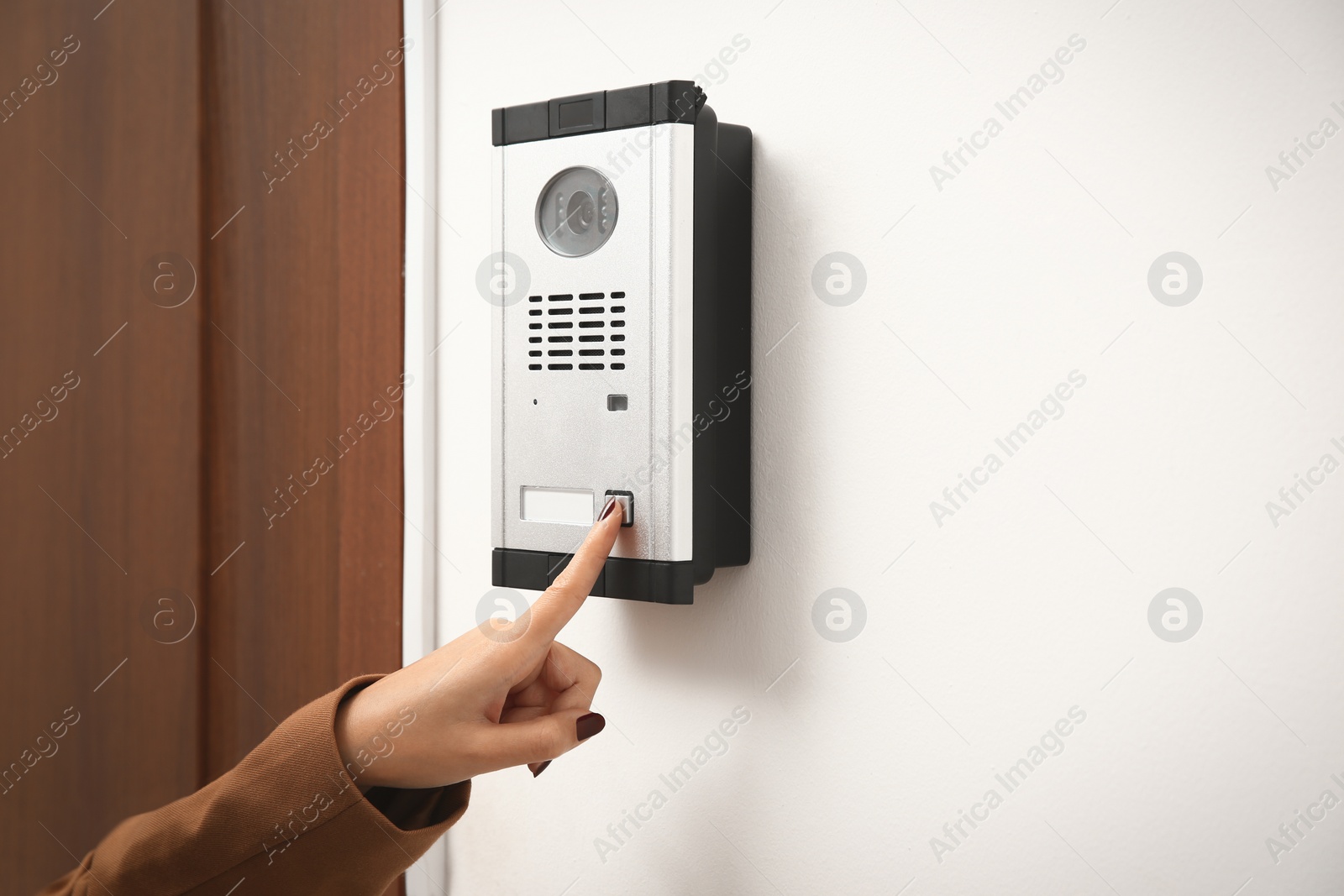 Photo of African-American woman ringing intercom with camera in entryway, closeup