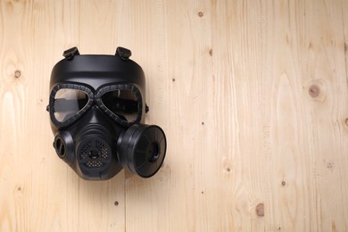 Photo of One gas mask on wooden background, top view. Space for text