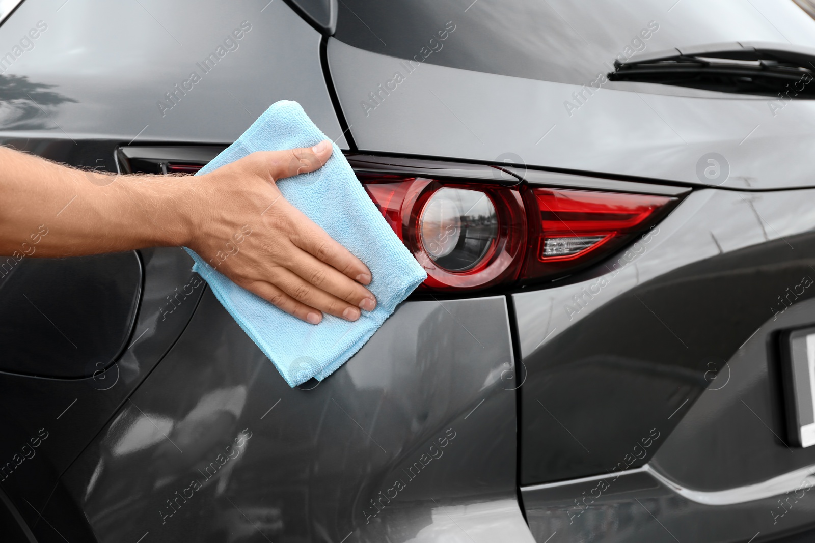 Photo of Man washing car headlight with rag, closeup