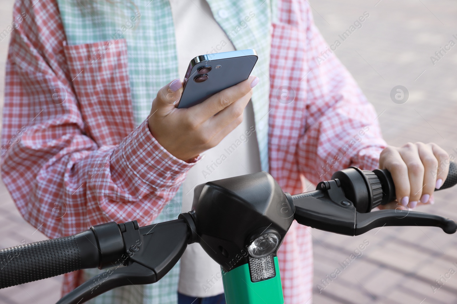 Photo of Woman using smartphone to pay and unblock electric kick scooter outdoors, closeup