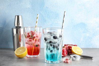 Photo of Tasty cocktails with fruit ice cubes on table against color background