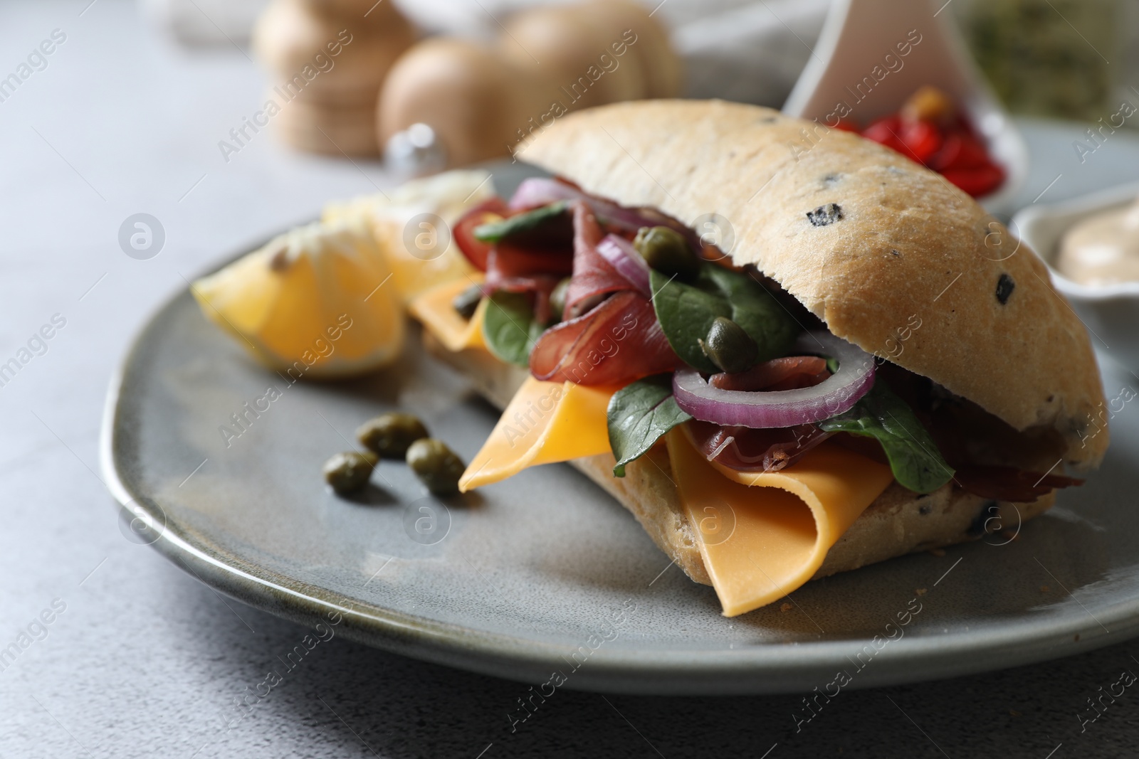 Photo of Delicious sandwich with bresaola, cheese and onion served on light grey table, closeup