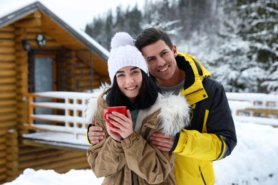 Happy couple with hot drink at resort. Winter vacation