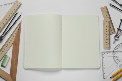 Photo of Different rulers, pencils and notebook on white background, top view. Space for text