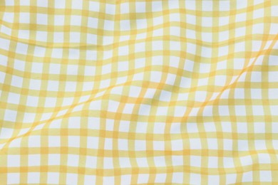 Yellow checkered picnic tablecloth as background, top view