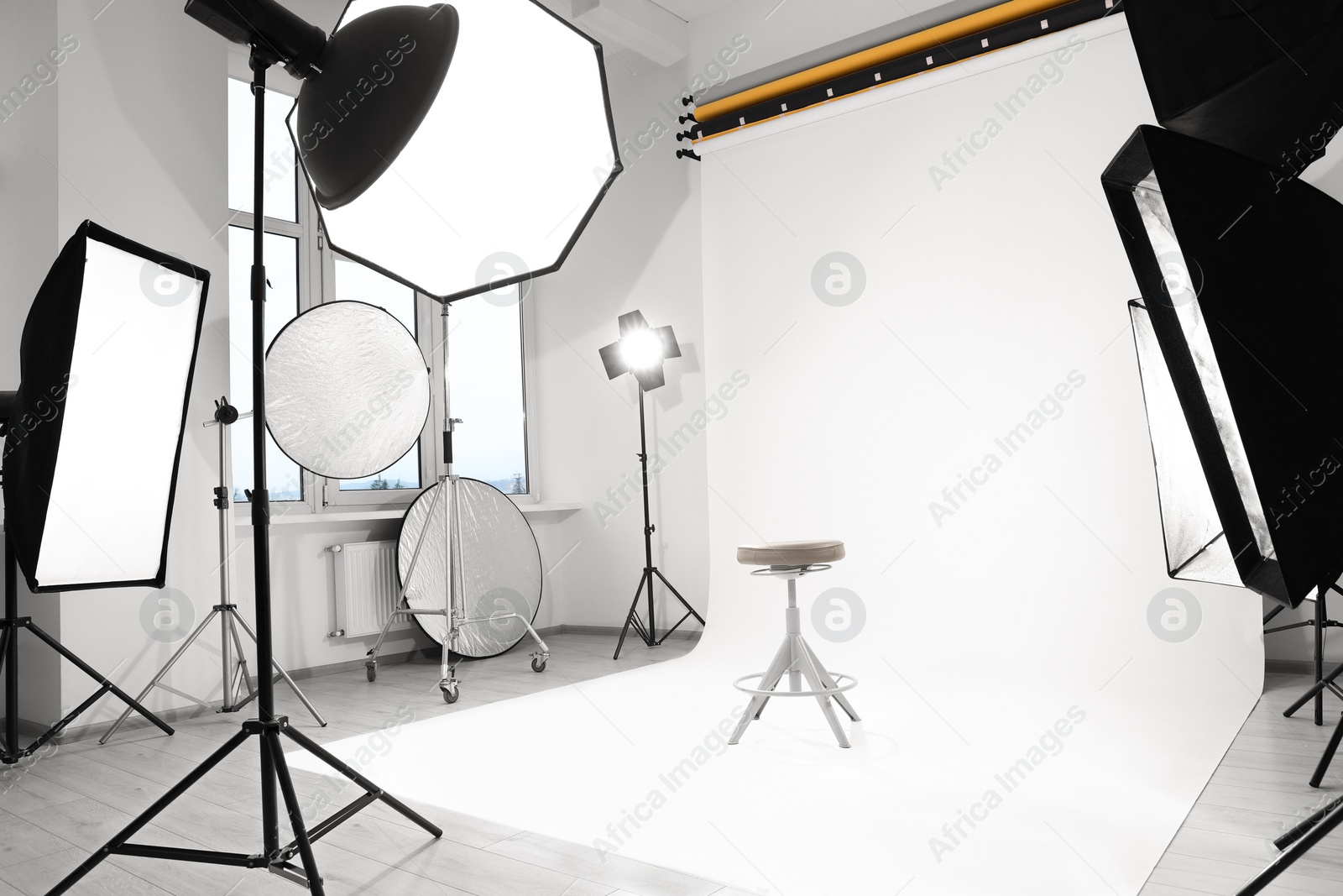 Photo of Interior of modern photo studio with bar stool and professional lighting equipment