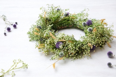 Photo of Beautiful wreath made of wildflowers on white table