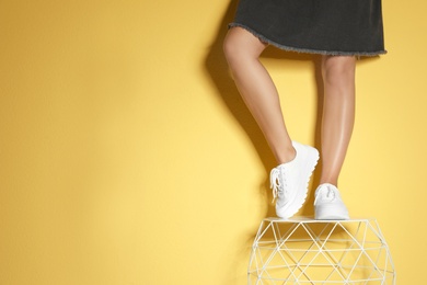 Photo of Woman in stylish sneakers near color wall, closeup. Space for text