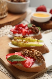 Photo of Board with different tasty ricotta bruschettas on table, closeup