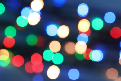 Blurred view of Christmas lights on color background