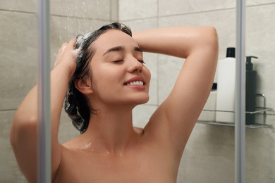 Photo of Happy woman washing hair in shower stall