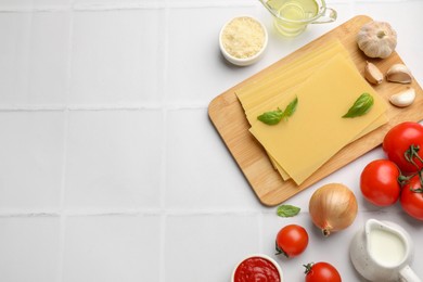 Photo of Ingredients for lasagna on white tiled table, flat lay. Space for text