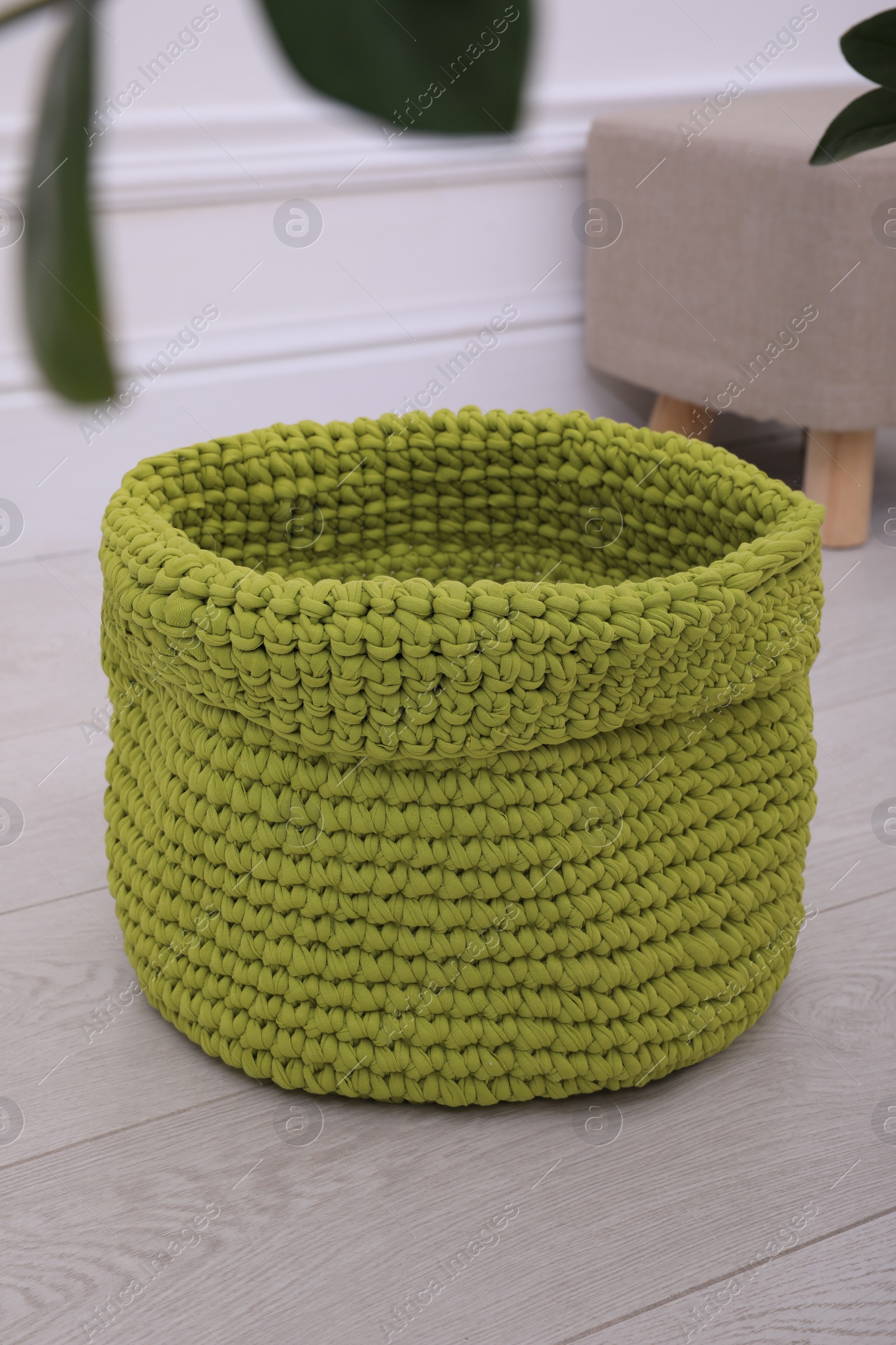 Photo of Empty knitted flowerpot cover on floor indoors