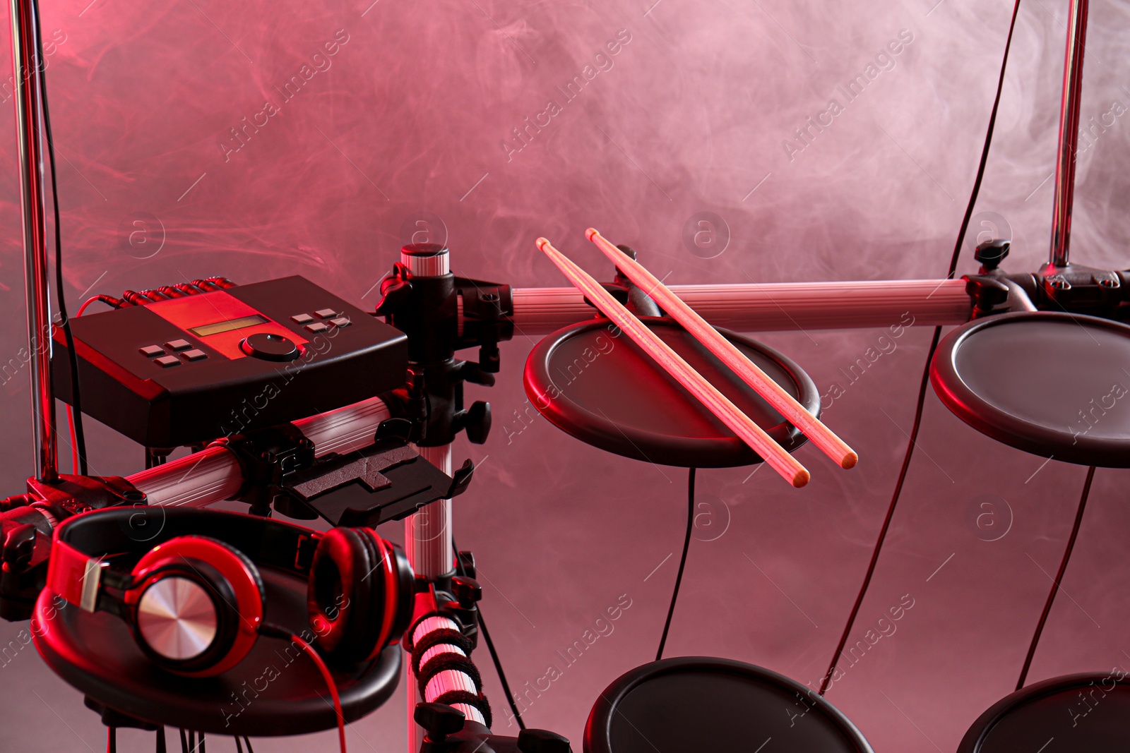 Photo of Modern electronic drum kit and smoke on grey background, toned in pink. Musical instrument