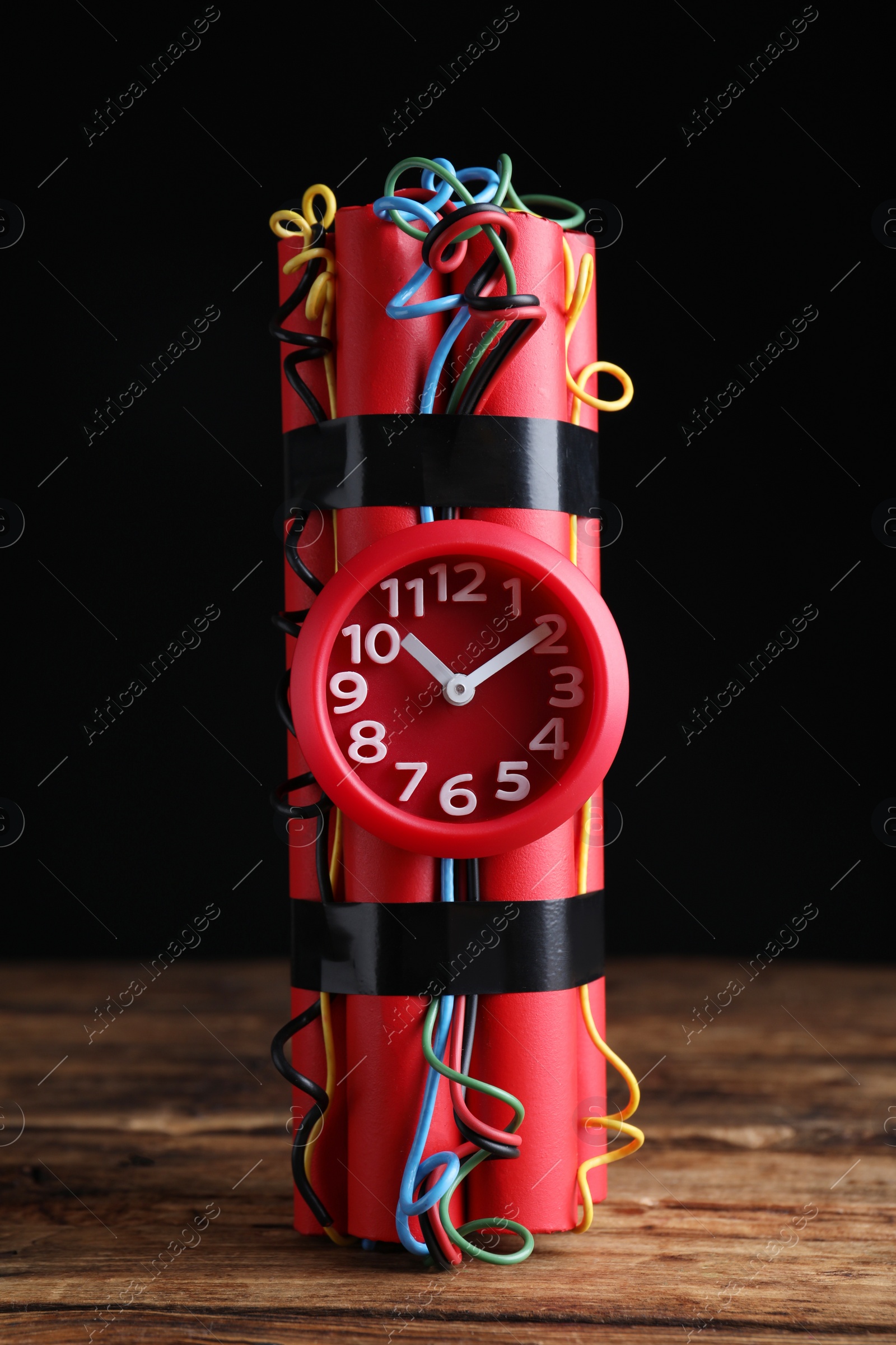 Photo of Dynamite time bomb on wooden table against black background