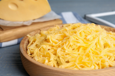 Photo of Tasty grated cheese on light grey wooden table, closeup