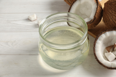 Photo of Coconut oil on white wooden table, closeup