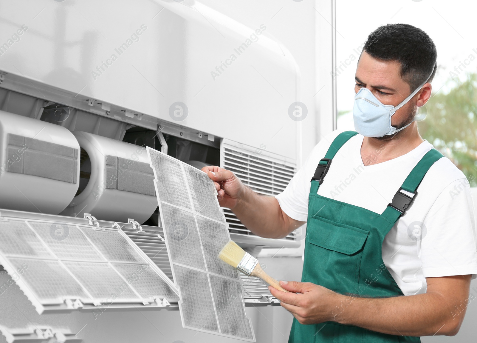 Photo of Professional male technician cleaning air conditioner indoors. Repair and maintenance