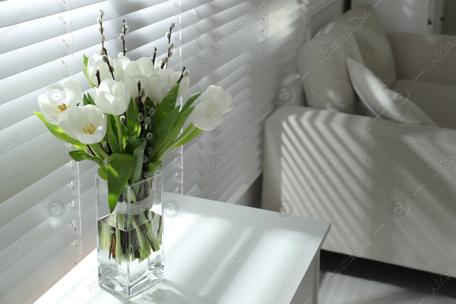 Photo of Beautiful bouquet of willow branches and tulips in vase near window indoors, space for text