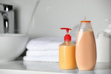 Shampoo and liquid soap near sink on bathroom counter, space for text