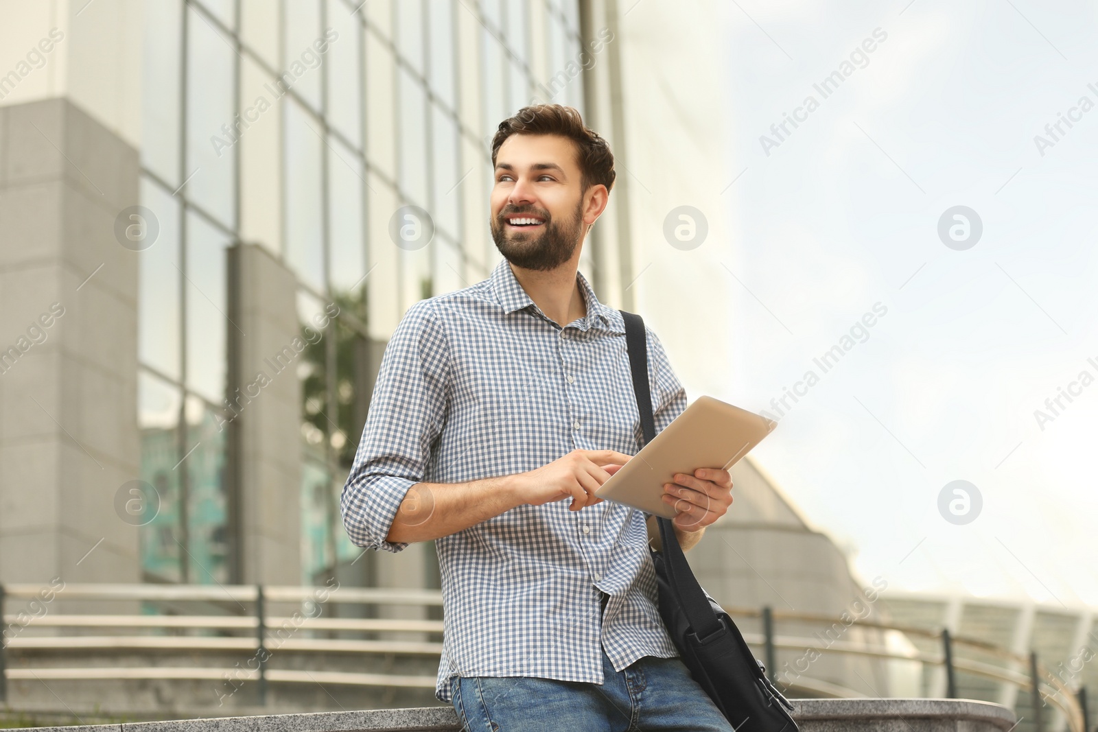 Photo of Handsome man working with tablet on city street