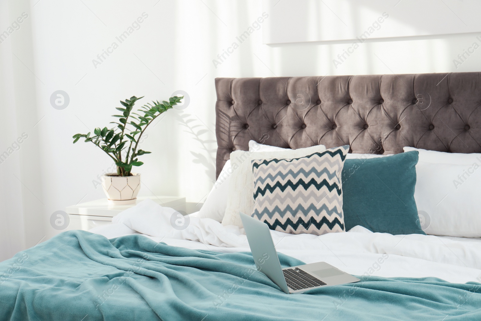 Photo of Laptop on bed in stylish room interior