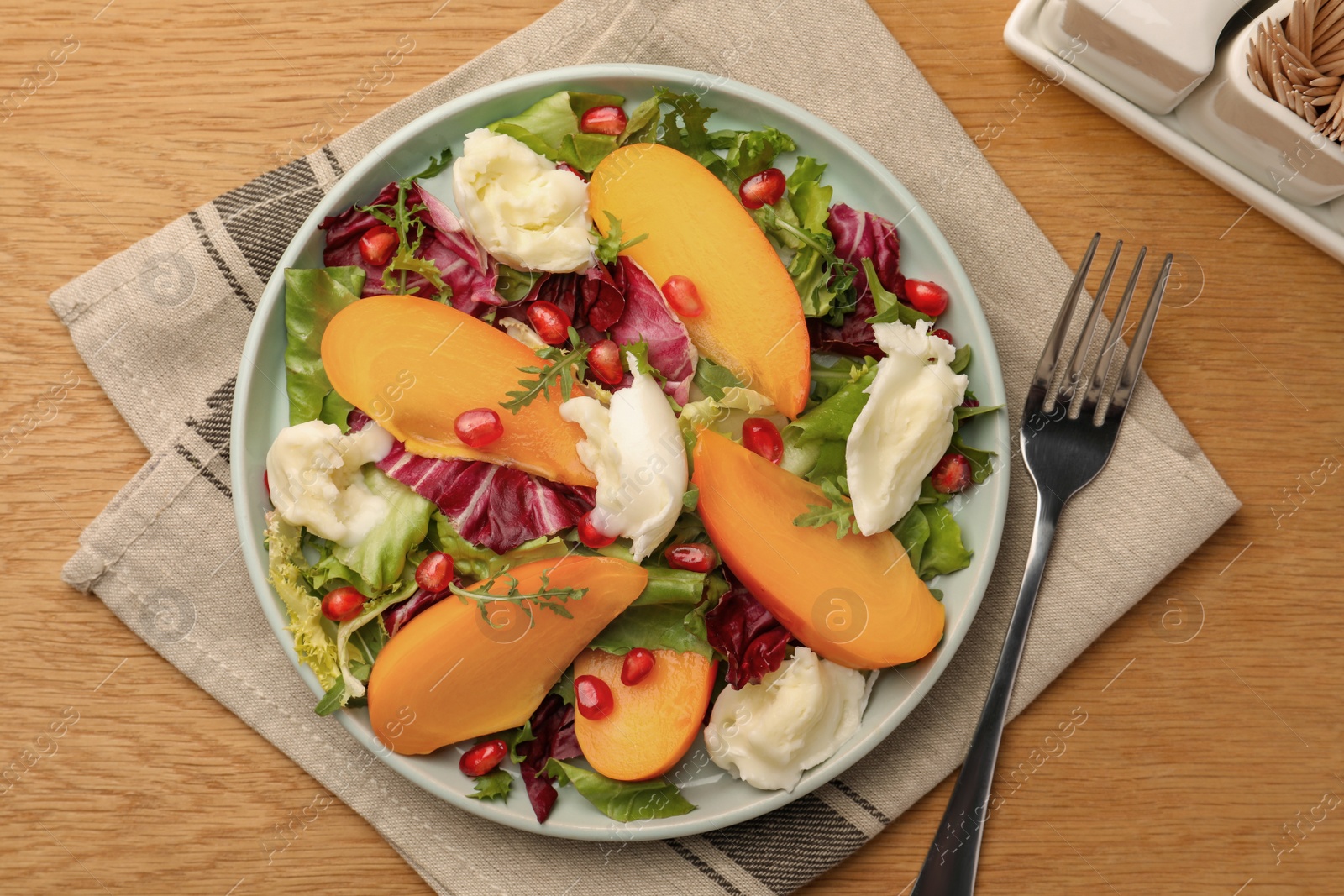 Photo of Delicious persimmon salad with cheese and pomegranate served on wooden table, flat lay