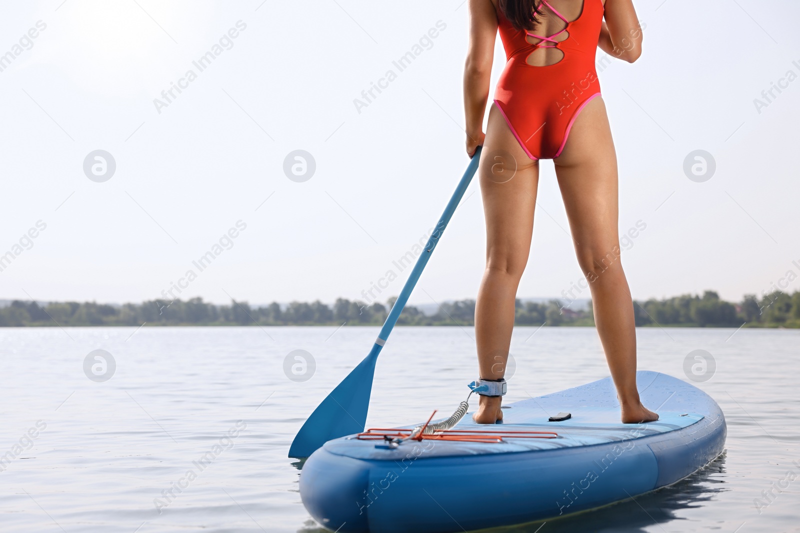 Photo of Woman paddle boarding on SUP board in sea, back view. Space for text