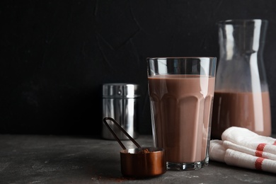 Photo of Glass with tasty chocolate milk on gray table, space for text. Dairy drink