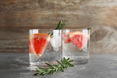 Glasses of infused water with grapefruit slices on table