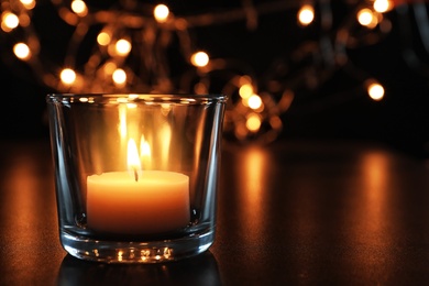 Wax candle burning on table in darkness, closeup