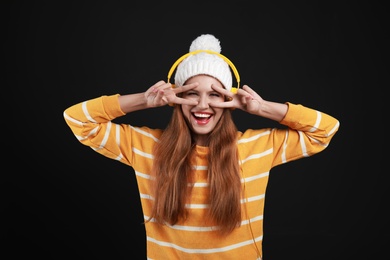 Young woman listening to music with headphones on black background