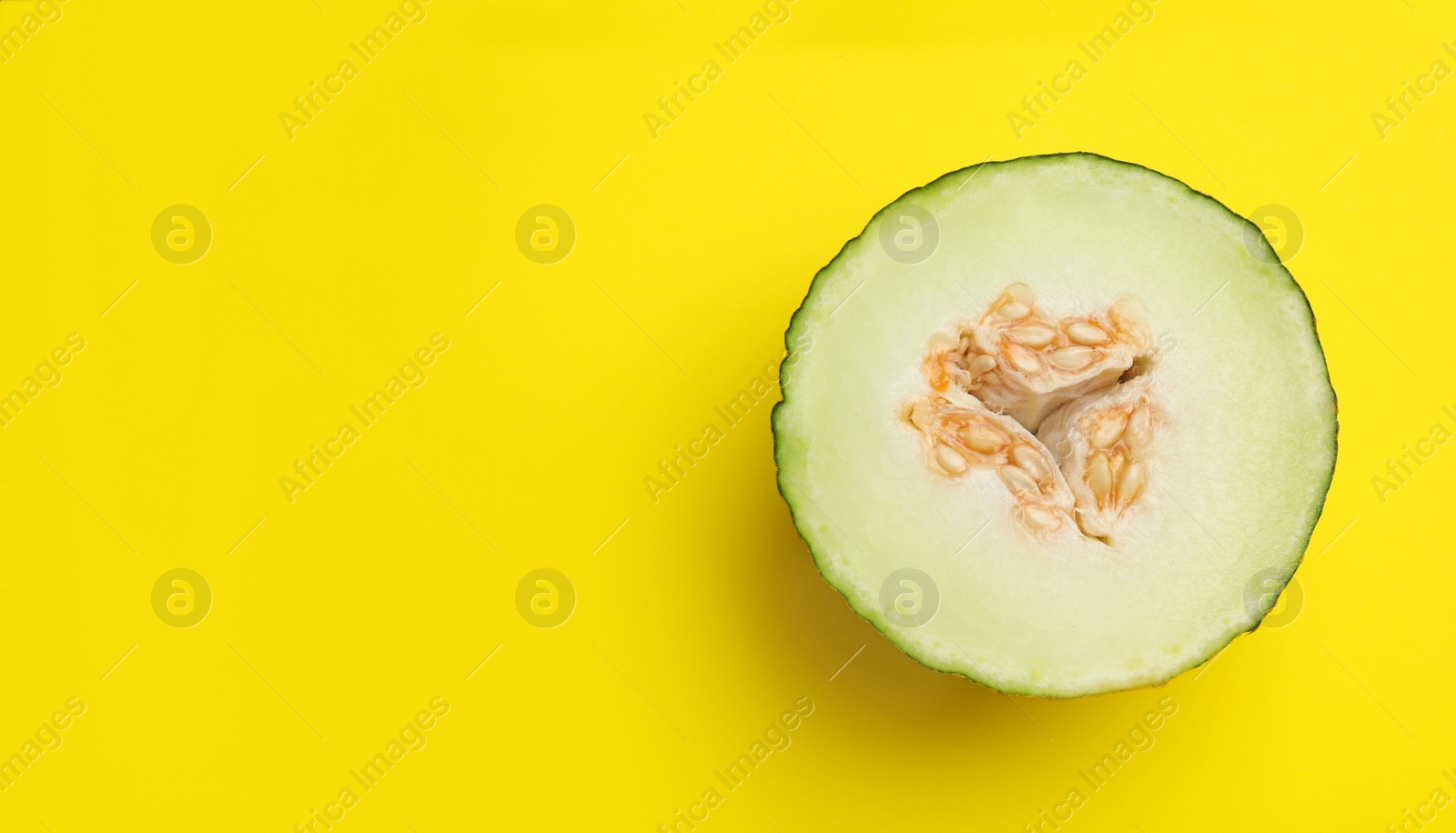 Photo of Half of ripe tasty melon on yellow background, top view. Space for text