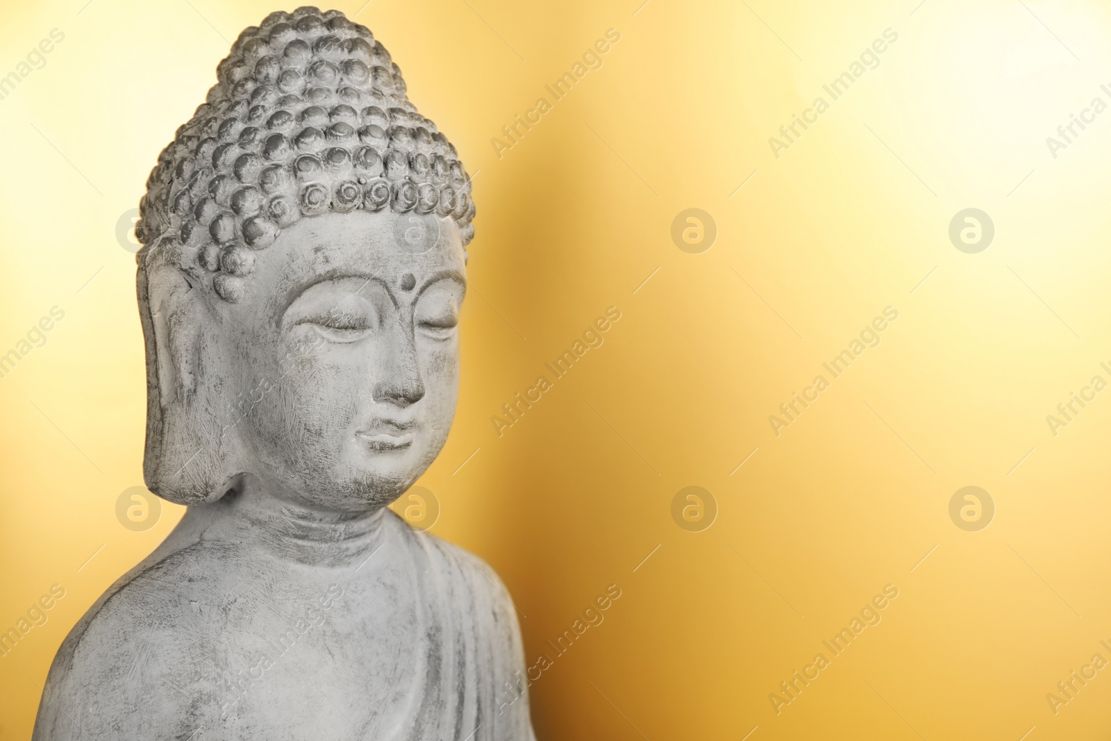 Photo of Buddha statue on golden background, closeup. Space for text