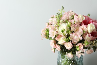 Photo of Beautiful bouquet of fresh flowers in vase on light background. Space for text