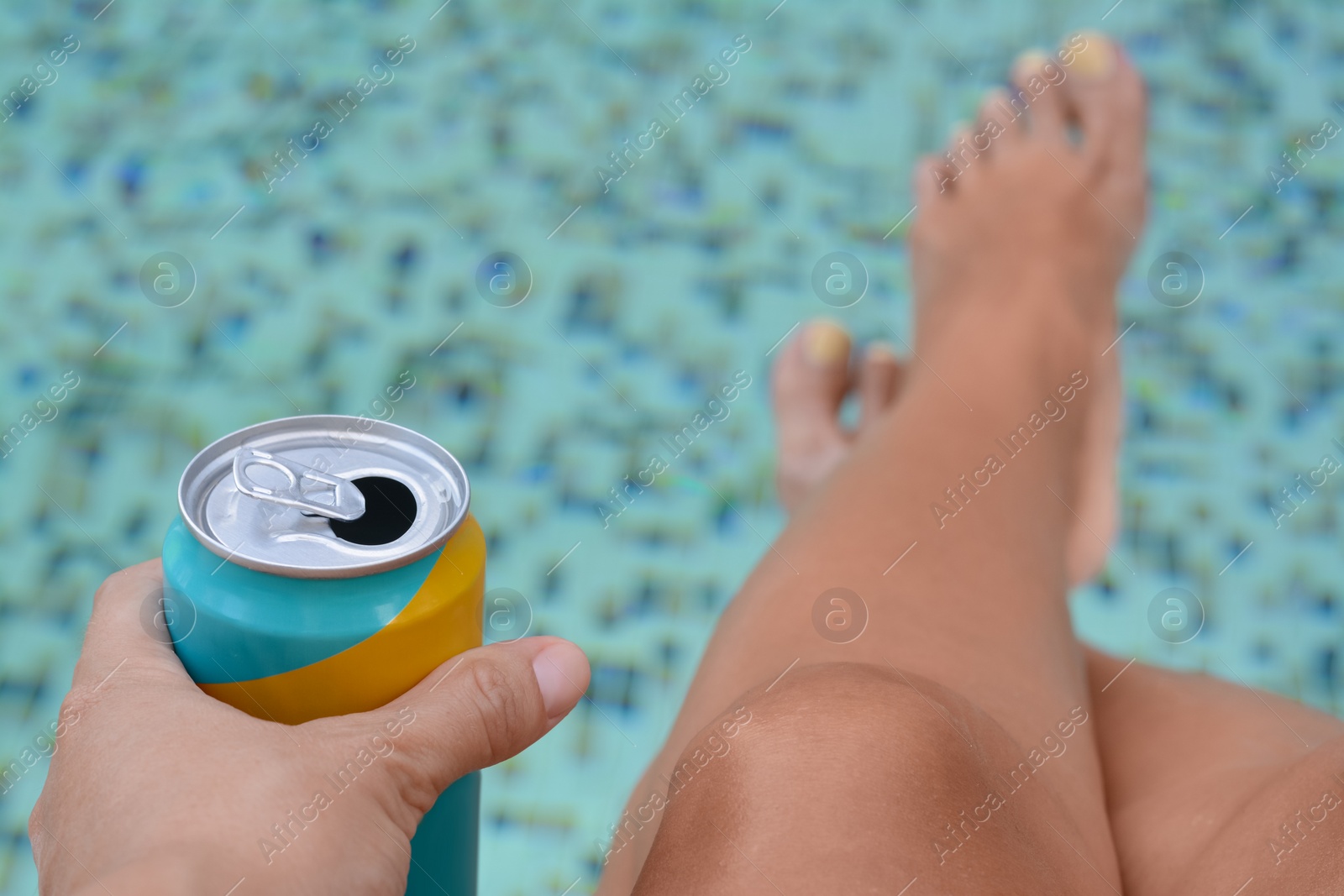 Photo of Woman holding aluminum can with beverage near swimming pool, closeup