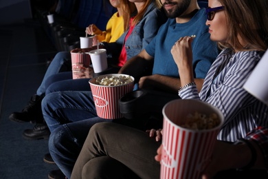 Young people eating popcorn during showtime in cinema theatre
