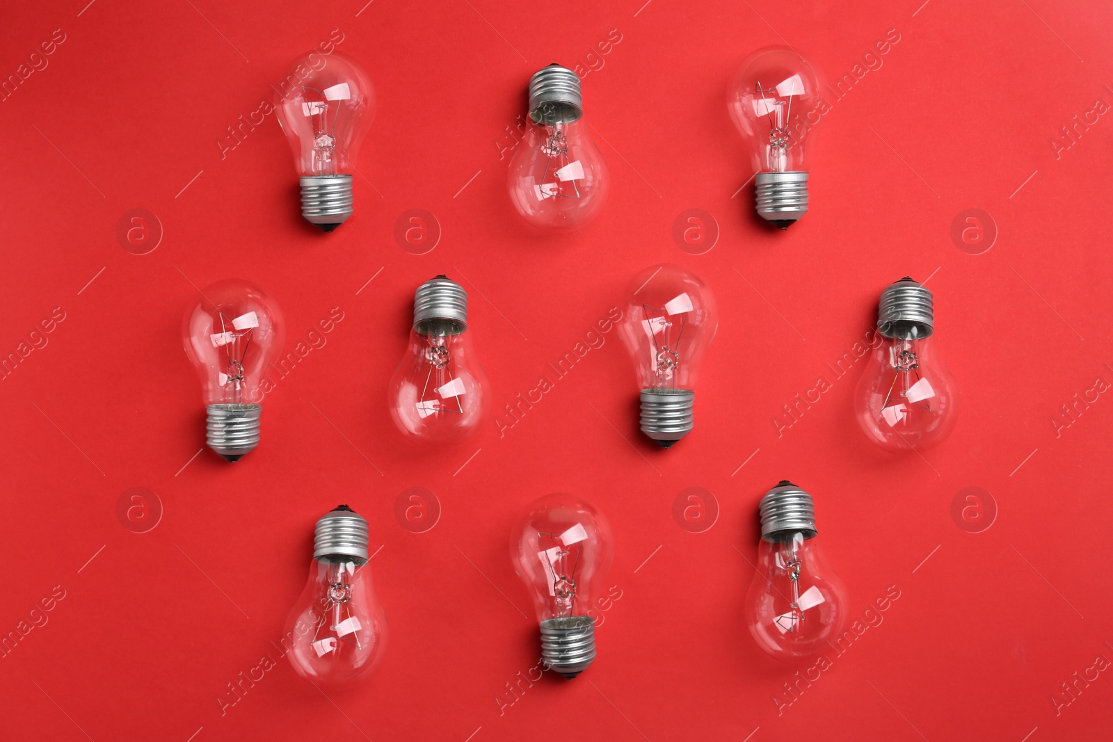 Photo of New incandescent lamp bulbs on red background, flat lay