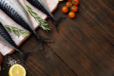 Photo of Raw mackerel, tomatoes and rosemary on wooden table, flat lay. Space for text