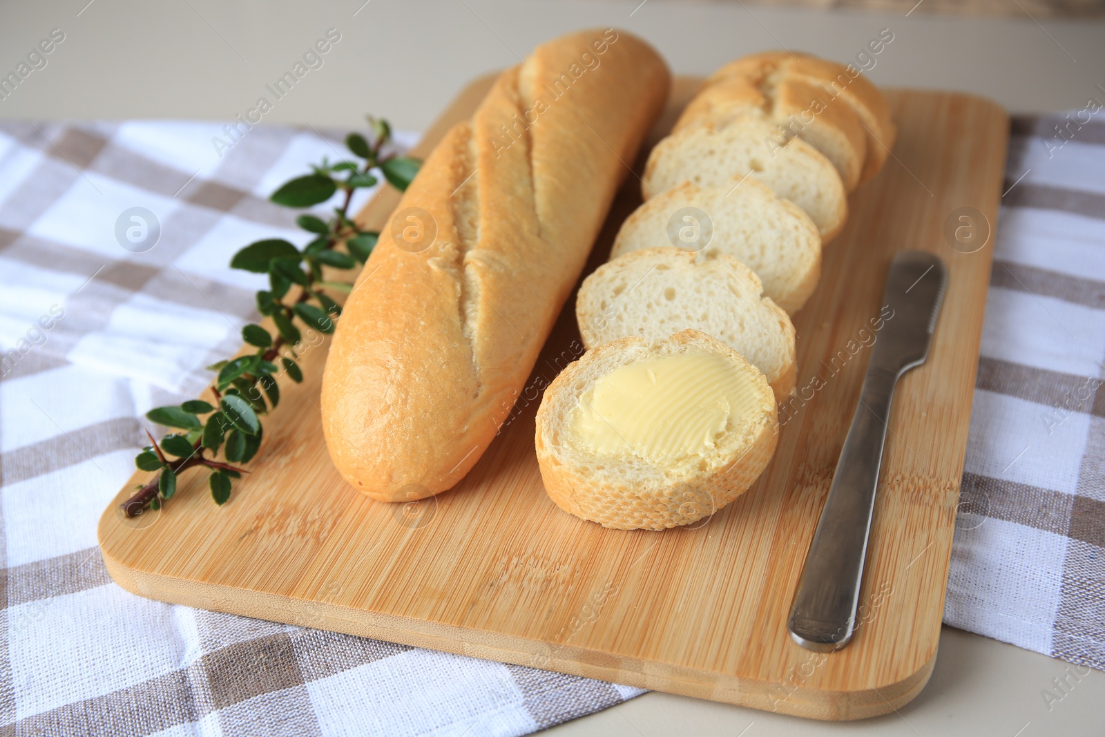 Photo of Whole and cut baguettes with fresh butter on table