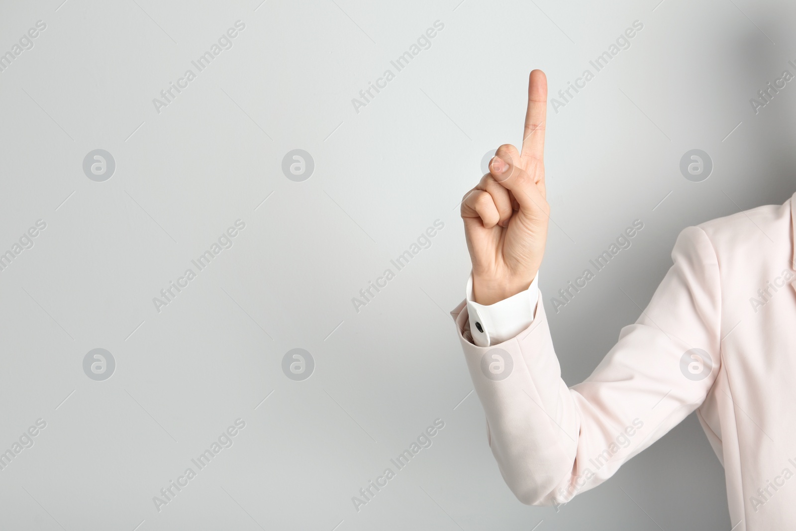 Photo of Young woman with raised index finger on light background. Space for text