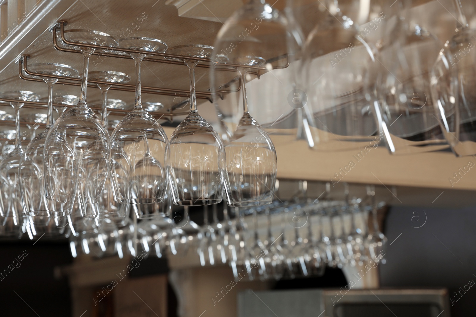 Photo of Set of empty clean glasses on bar racks