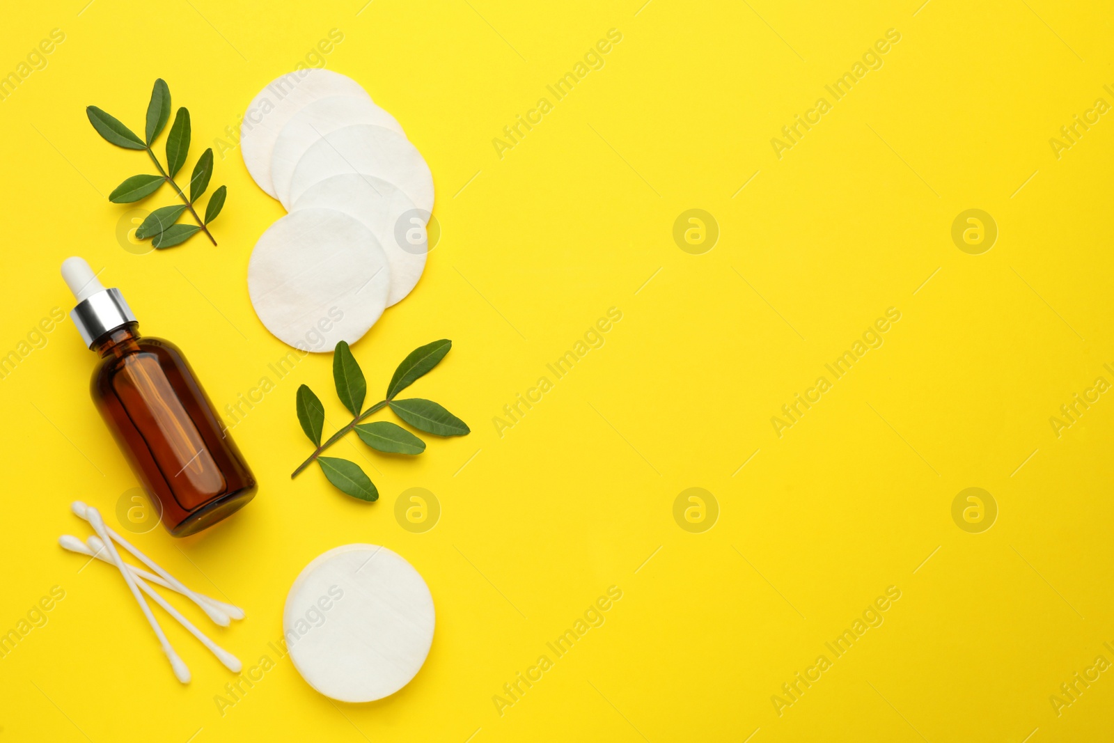 Photo of Cotton pads, swabs and makeup removal product on yellow background, flat lay. Space for text