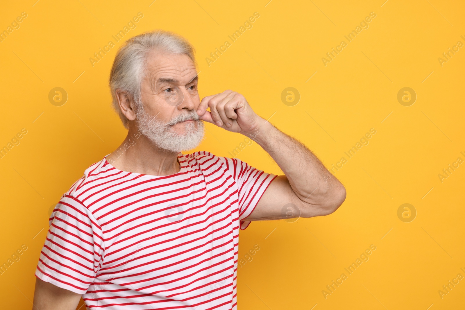 Photo of Senior man touching mustache on orange background, space for text