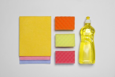 Photo of Sponges and other cleaning products on white background, flat lay