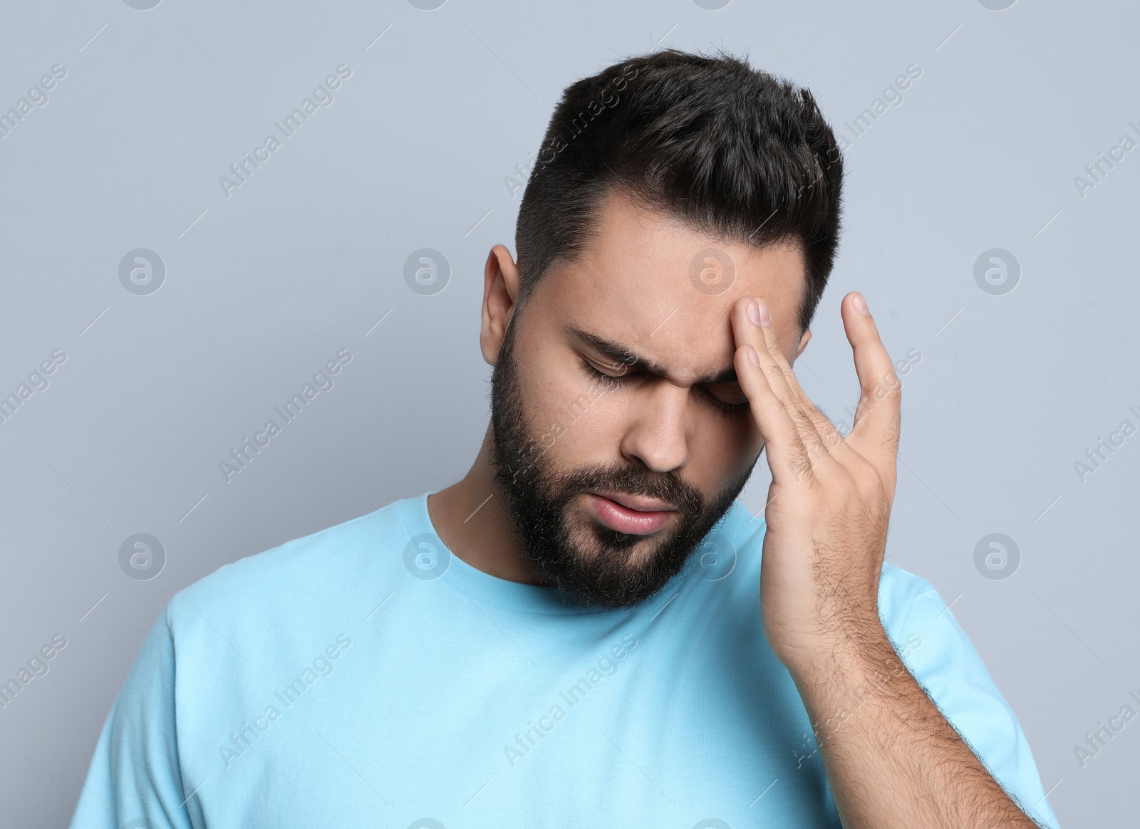 Photo of Young man suffering from headache on light grey background